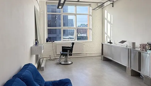 A barber chair by the tall windows